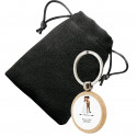 Porte-clés en bois circulaire personnalisé avec autocollant de mariage et présenté dans un sac en suédine.