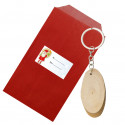 Porte-clés en bois présenté dans une enveloppe kraft rouge avec un autocollant pour Noël