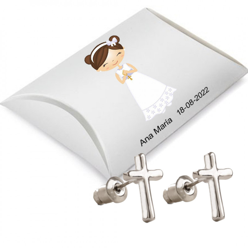 Boucles d'oreilles en forme de croix présentées dans une boîte en carton argenté et un autocollant de communion avec un nom