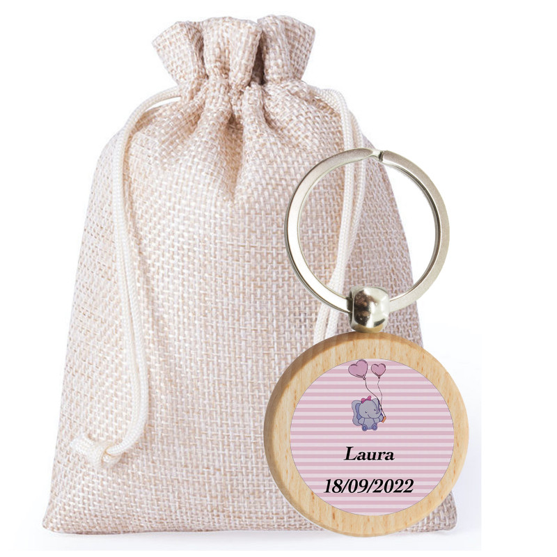 Porte-clés de baptême personnalisé pour fille présenté avec un sac