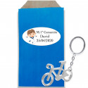Porte-clé en forme de vélo en argent dans une enveloppe kraft avec un autocollant personnalisé pour la communion d'un garçon